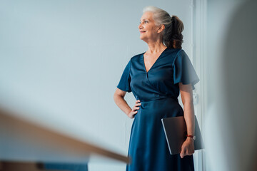 Smiling businesswoman with laptop standing in office