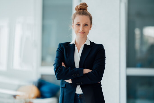 Confident businesswoman with arms crossed standing at office