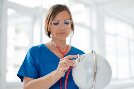 Doctor examining globe with stethoscope at clinic