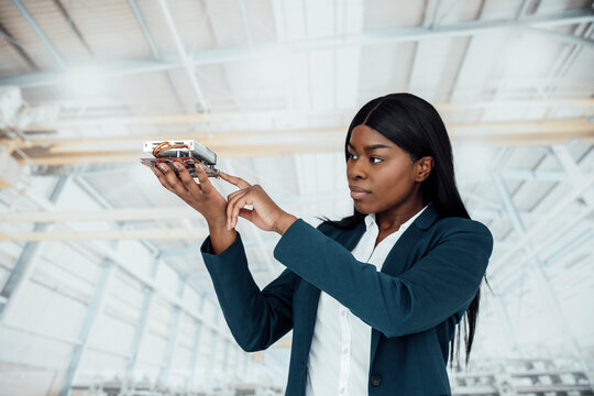 Businesswoman analyzing machine part standing in factory