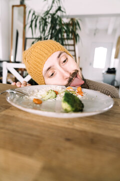 Hungry man licking plate with broccoli