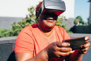 Playful woman wearing virtual reality holding smart phone on sunny day