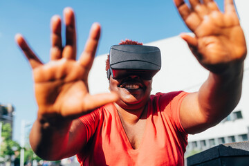 Happy woman wearing virtual reality simulator gesturing on sunny day