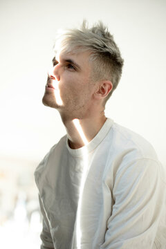 Man with beam of light on face sitting against white background