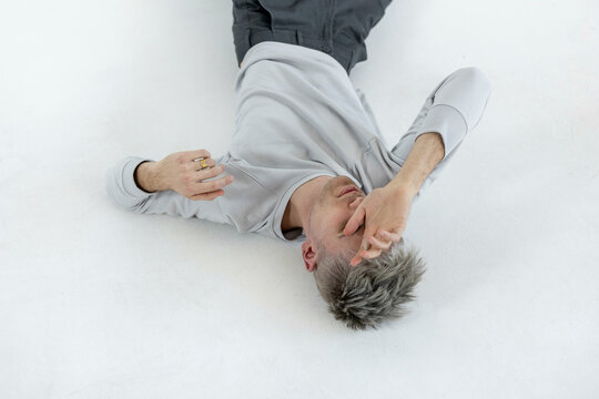 Young man lying on white floor