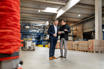 Businessman planning strategy with colleague over tablet PC in warehouse