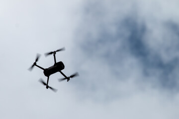 A silhouette of a consumer drone in the sky with clouds