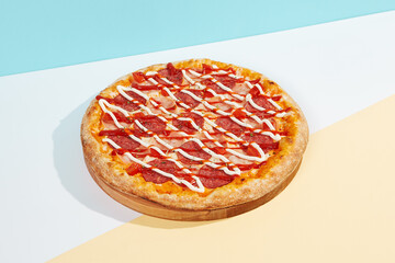 Italian pizza with ham and salami on coloured background. Meat pizza with ham, ketchup and mayonnaise in minimal style on blue colour. American pizza delivery concept with color backdrop