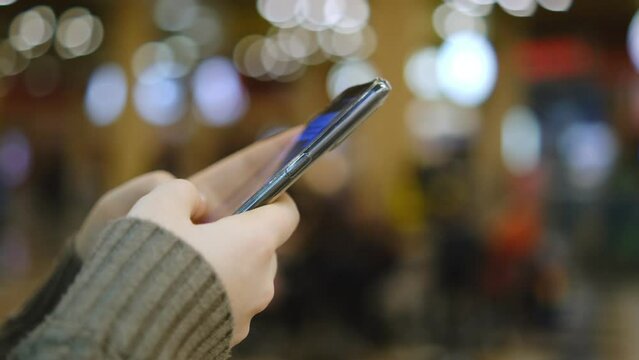 Shopping center. Moll. Finger of woman touching scroll page app on mobile phone. Browsing movie video in the internet library to watch film online.