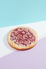 Italian pizza with fruit and berries on coloured background. Sweet pizza with bananas, berries and sauce in minimal style on blue color. American pizza delivery concept with color backdrop.