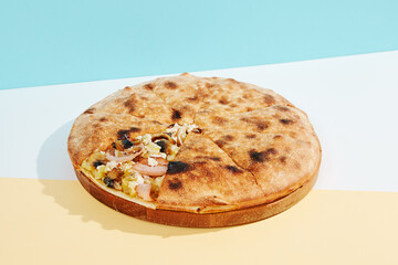Italian closed pizza with mushroom, potatoes and chicken on coloured background. Mushroom pie with chicken and potatoes in minimal style. American pizza delivery concept with color backdrop.