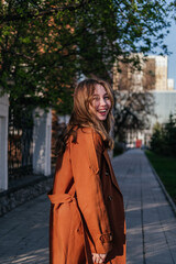 Fototapeta premium Portrait of smiling young woman in coat looking away outdoors. Girl in city