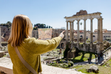 A happy blond woman tourist is standing near the Roman Forum, old ruins at the center of Rome,...