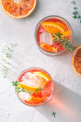 Red cocktail with Campari or bitter, Spritz  with  Sicilian red oranges (tarocco) on light gray concrete background, copy space. Aperitif, natural eco aesthetic, white background, top view