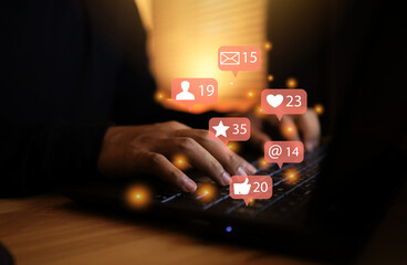 Hands are typing on a laptop keyboard or using a laptop to use social media to communicate with social community networks, and icons float from the keyboard to send messages appointments love stars.