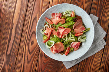 Delicious salad with prosciutto, mix of salads and tomatoes.