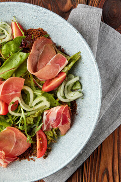 Delicious salad with prosciutto, mix of salads and tomatoes.
