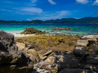 Rocky sea beach bright clear water blue sky with cloud