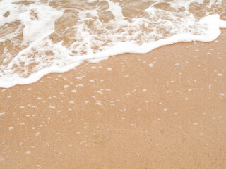 high angle view. Ocean waves hit the beach or shore and air bubbles. Wet sand, sea water and empty space.