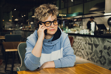 stylish woman casual wear portrait in public cafe - working with mobile