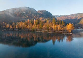 Obraz premium Lake Bled on a foggy and misty autumn morning. Vivid sunrise on a beautiful autumn day.