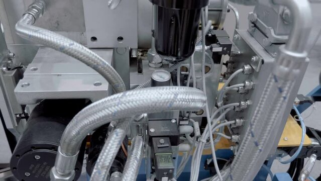 A unit of industrial equipment where the accumulation of hydraulic hoses, valves, filters and pumps ensures the operation of the mechanism. Close up. Shot in motion