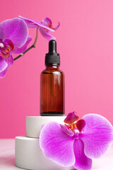 Fototapeta na wymiar Beauty collagen face oil in a glass dropper bottle on podium with orchid flowers. Trendy shoot of cosmetics packaging. Essential oil with natural ingredients.