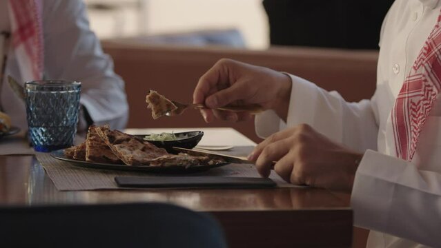 A customer eating a meat stuffed flat bread with a white sauce. A Restaurant dinning