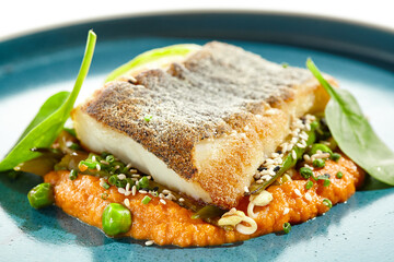 Gourmet dish - salmon with crispy skin with carrots mash. Grilled salmon fillet on carrot espuma. Keto food - baked trout with skin on white background and hard shadow. Menu seafood restaurant.