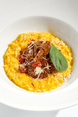 Risotto alla milanese with meat ragu. Saffron risotto with lamb meat isolated on white background. Yellow risotto in white plate. Italian classic cuisine in restaurant menu.
