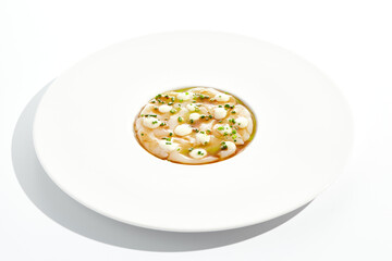 Delicious food - sea scallop carpaccio in yuzu sauce on white background. Scallop ceviche in japanese style. Scallop crudo in citrus sauce and creamy espuma. Delicacy seafood in restaurant menu.