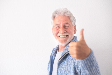 Portrait of handsome bearded senior man in casual clothes with thumb up smiling and looking at the camera while standing on white background