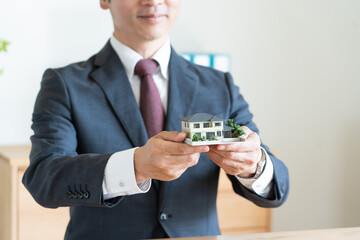 住宅の模型を持つビジネスマン