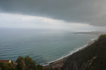 The beautiful sea surrounding Sicily on a cloudy day with waves crashing against the rocks