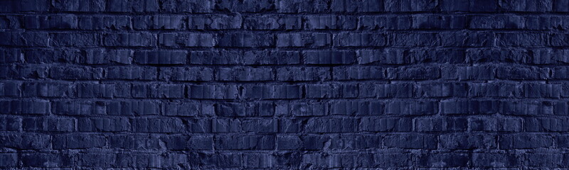 Navy blue old rough brick wall wide texture. Dark exterior brickwork masonry long backdrop. Gloomy...