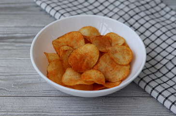 Bowl with delicious potato chips with paprika on a silver table