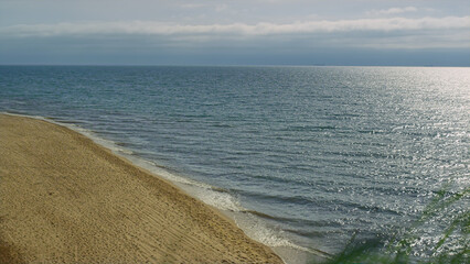 Fototapeta na wymiar Grass moving sea beach outdoors. Ocean waves crashing in sand shore top view. 