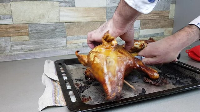 the cook cuts into pieces a pig baked in the oven. portioned distribution of a beautiful pork dish to the table. suckling pig