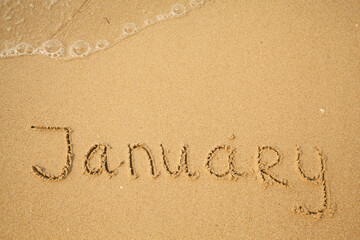 January - drawing handwritten on the sea beach sand.