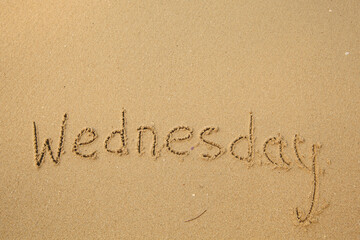 Wednesday - drawing of days of the week, handwritten on the sea beach sand.