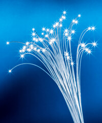 Bundle of optical fibers with lights in the ends. Blue background.