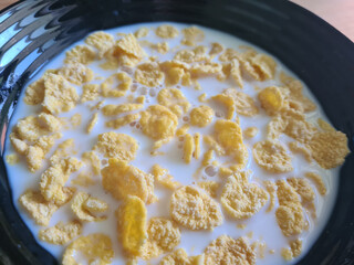 Corn sweet flakes in milk in black plate closeup