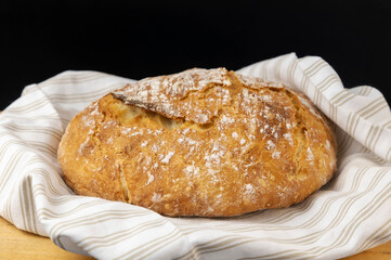 Homemade bread. Freshly baked round bread on a wooden background, put on a light colored towel.