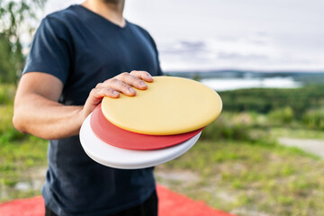 Disc golf player with frisbee equipment in park course. Man playing discgolf. Outdoor sport tournament. Summer landscape in Finland. - obrazy, fototapety, plakaty