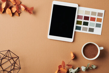 Top view of workplace of designer with tablet, color swatches, cup of coffee, handmade vase and dry...