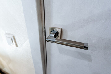 Door handle chrome plated, door to the room locked, door handle shot close-up, grey door, interior...
