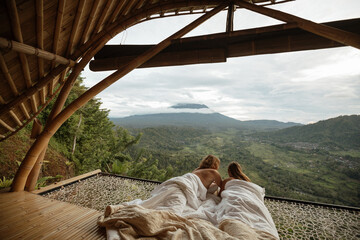 Couple in love covering a white blanket lying in a hammock at the view of nature of mountains with...