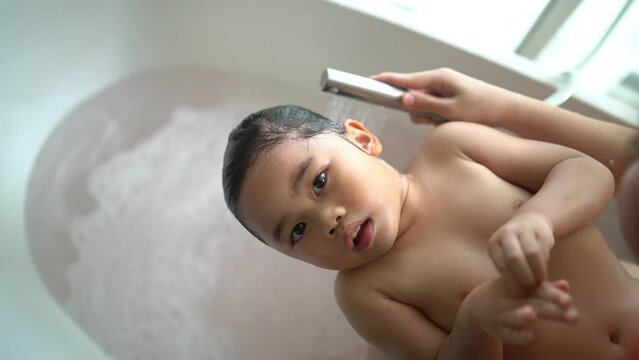 Asian baby girl happy taking a bath and washing hair with mother at home, asian child baby shower. Baby family concept.