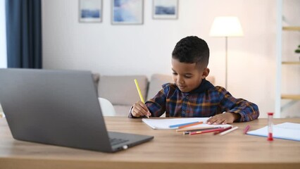 Learning to draw. Cute african american boy is indoors in domestic room