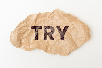 Crumpled craft paper with the inscription: TRY.  Creative motivation text. A motivate call to action.  White background.